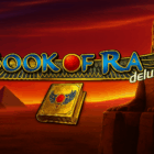 Logo della slot Book of Ra Deluxe con sfondo egiziano, piramidi e statua del faraone al tramonto
