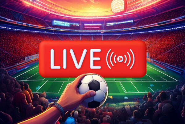 Live Betting Scritta in primo piano“Live”, mano che tiene un pallone di calcio e sullo sfondo un campo di calcio pieno di tifosi
