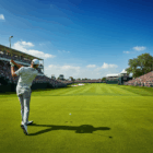 Campo da golf durante l'Open Championship 2025 con un golfista catturato nel momento dello swing, un fairway verde e rigoglioso, e una folla di spettatori sotto un cielo soleggiato.