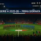 Serie A 2025-26, prima giornata: stadio sold-out al crepuscolo, bandiere tricolori, due squadre in fila (rossoneri vs blu), tabellone 0-0 e scritta “Serie A 2025-26 – Prima giornata” con orario 23 agosto 18:30; nessun logo ufficiale.