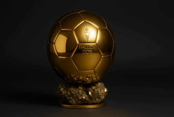 Trofeo del Pallone d’Oro 2025, il celebre premio calcistico dorato su basamento nero illuminato da riflettori, su sfondo elegante e scuro.