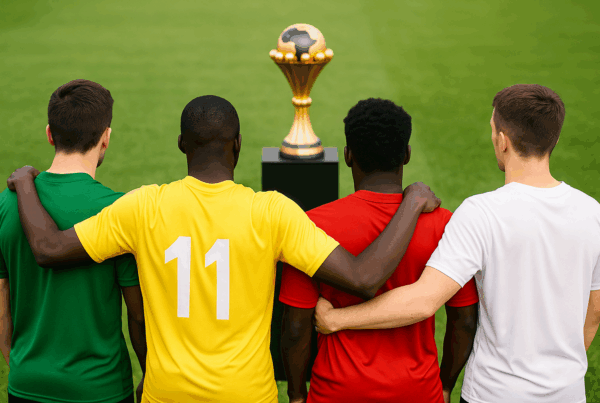 Giocatori di calcio di diverse etnie visti di spalle che osservano la Coppa d’Africa su un piedistallo in uno stadio. Chi partecipa alla Coppa d’Africa