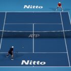 Veduta dall’alto di un campo blu delle ATP Finals con due giocatori non riconoscibili durante il match, immagine riferita a Sinner in semifinale ATP Finals 2025.