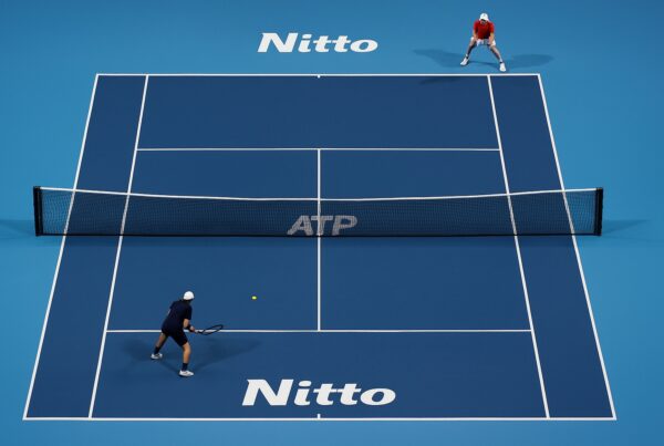 Veduta dall’alto di un campo blu delle ATP Finals con due giocatori non riconoscibili durante il match, immagine riferita a Sinner in semifinale ATP Finals 2025.