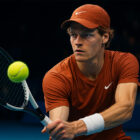 Tennista in azione durante un match indoor, colpo di rovescio in primo piano con espressione intensa e illuminazione cinematografica, stile realistico 3D.