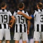 Bonucci, Barzagli e Chiellini di spalle in maglia bianconera, schierati in campo sotto le luci dello stadio: la storica BBC Juventus.