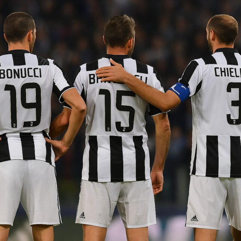 Bonucci, Barzagli e Chiellini di spalle in maglia bianconera, schierati in campo sotto le luci dello stadio: la storica BBC Juventus.