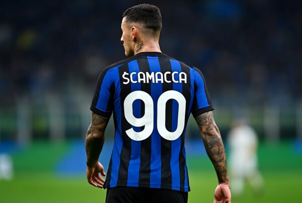 Scamacca di spalle in campo con maglia nero-azzurra numero 90: immagine di copertina per l’articolo quanto guadagna Scamacca