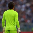 Portiere di calcio di spalle in divisa verde fluo, guanti bianchi e neri, fermo in campo con lo stadio sfocato sullo sfondo che rappresenta l'articolo del blog di quogioco Quanto guadagna Sommer