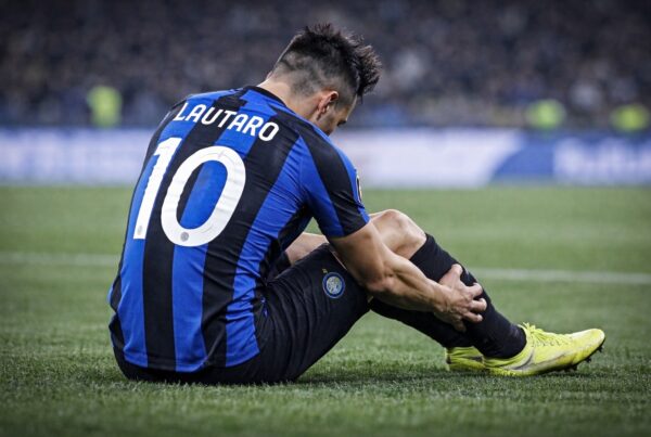 Calciatore seduto sul campo da calcio di spalle mentre si tiene il polpaccio dolorante dopo un infortunio in rappresentanza di inter lautaro infortunio