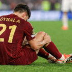 Nuovo Infortunio Dybala: Paulo Dybala di spalle seduto sul campo mentre tiene il ginocchio dolorante durante una partita della Roma.