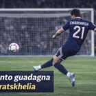 Khvicha Kvaratskhelia di spalle con la maglia del PSG mentre calcia di destro verso la porta con la scritta Quanto guadagna Kvaratskhelia