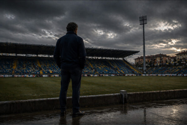 Uomo di spalle osserva uno stadio vuoto durante il fallimento Parma 2015 sotto un cielo cupo
