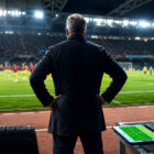 Queiroz osserva il campo da calcio durante una partita internazionale in uno stadio illuminato
