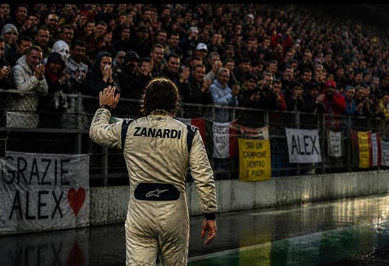 Morto Zanardi: pilota di spalle saluta i tifosi commossi sugli spalti durante l’uscita dalla pista
