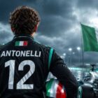 Kimi Antonelli posizione in classifica da leader del Mondiale Formula 1 2026 in una grafica sportiva con il pilota italiano ripreso di spalle accanto a una monoposto dai colori argento e turchese. Sullo sfondo sventola il tricolore italiano mentre il nome Antonelli e il numero 12 dominano la scena, simbolo della sua prima posizione nella classifica piloti F1 2026 con Mercedes.
