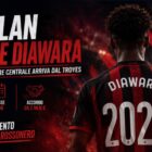 Il Milan prende Diawara: immagine editoriale con il giovane difensore di spalle mentre osserva uno stadio illuminato. Sullo sfondo dominano i colori rossoneri e il titolo della notizia annuncia l'arrivo del centrale francese dal Troyes.