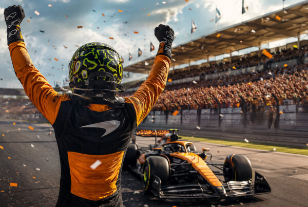 GP Ungheria 2026, pilota McLaren festeggia di spalle dopo la vittoria sul circuito con monoposto e tribune sullo sfondo.