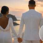 Cristiano Ronaldo sposato con Georgina Rodriguez, coppia ritratta di spalle mano nella mano durante una romantica cerimonia al tramonto, con dettaglio delle fedi nuziali.