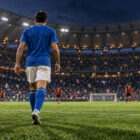 Italia-Belgio Mancini-bis: calciatore azzurro visto di spalle entra in campo davanti al pubblico dello stadio.
