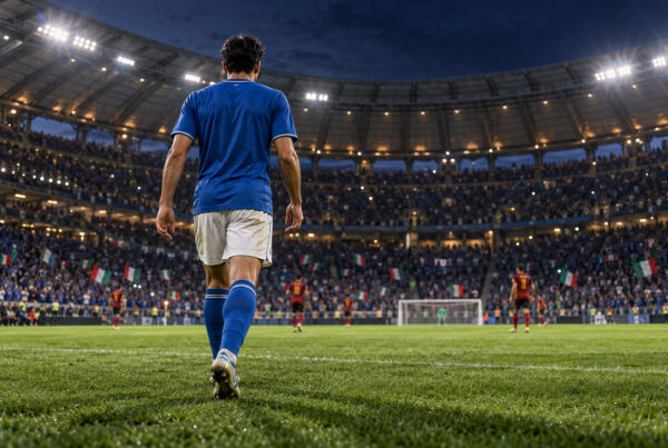 Italia-Belgio Mancini-bis: calciatore azzurro visto di spalle entra in campo davanti al pubblico dello stadio.