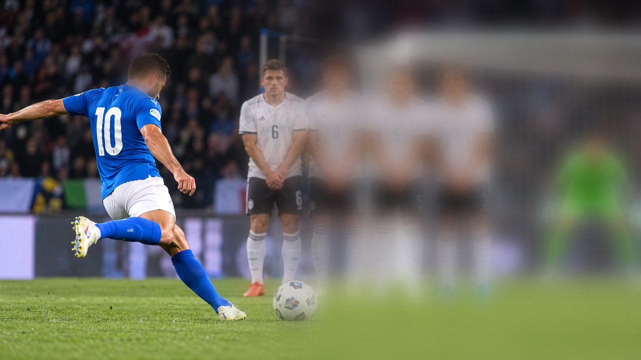 Calci di punizione nel calcio: giocatore al tiro davanti alla barriera difensiva