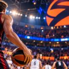 Eurolega basket 2026/27: giocatore di spalle con pallone durante una partita in un palazzetto illuminato.