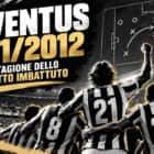 Juventus 2011 2012, giocatori bianconeri di spalle festeggiano lo Scudetto imbattuto in uno stadio illuminato, celebrando una stagione senza sconfitte.