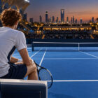 Sinner Six Kings Slam 2026: illustrazione di un tennista di spalle a bordo campo, con racchetta e skyline di Riad al tramonto.